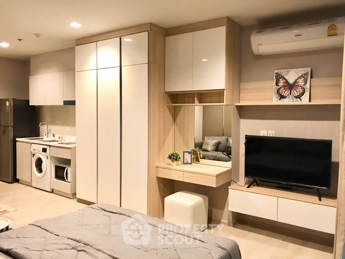 Modern studio apartment with kitchen and living area, featuring sleek furniture and appliances.