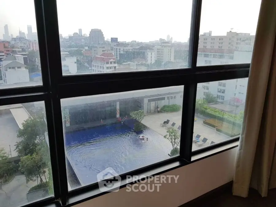 Stunning city view from high-rise apartment overlooking a luxurious pool area.