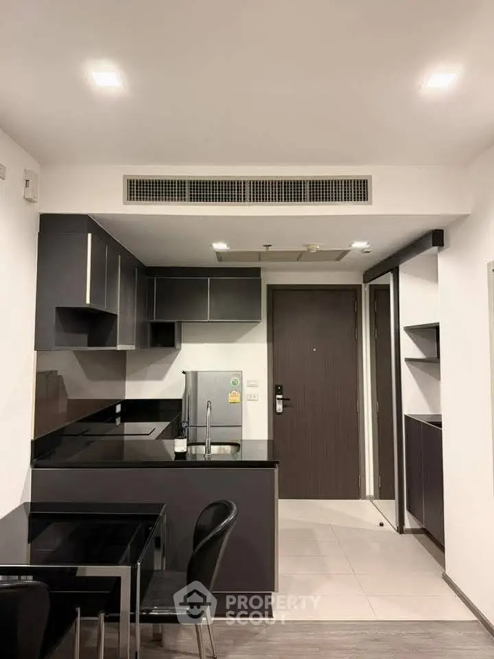 Modern kitchen with sleek black cabinetry and integrated appliances in a stylish apartment.