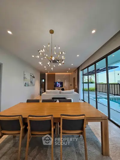 Luxurious open-plan living room with modern chandelier and pool view, perfect for entertaining.