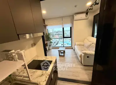 Modern compact living room with city view, featuring cozy sofa and sleek kitchen area.