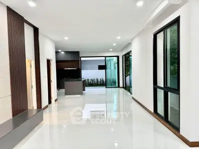 Spacious modern living room with open kitchen and large windows for natural light.