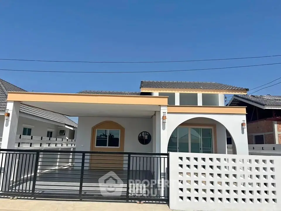 Modern single-story house with arched entrance and spacious driveway under clear blue sky.
