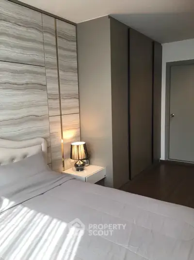 Modern bedroom with stylish decor and natural light, featuring a cozy bed and elegant lighting.