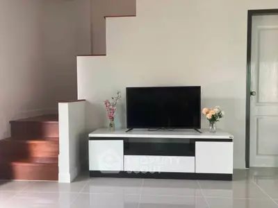 Modern living room with sleek TV stand and elegant staircase
