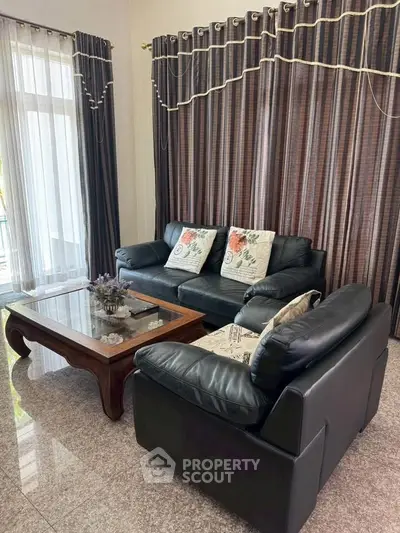 Elegant living room with black leather sofas and large windows for natural light.