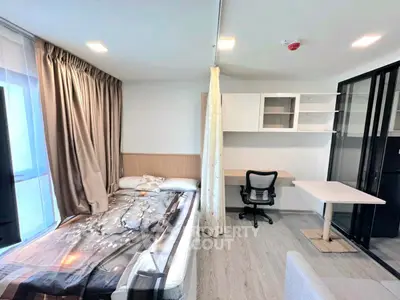 Modern studio apartment with bed, desk, and ample natural light