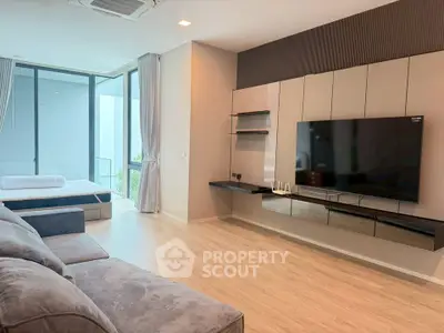 Modern living room with sleek design and large TV, featuring a cozy sofa and natural light.