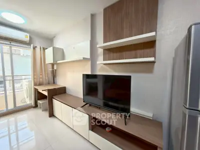 Modern living room with sleek furniture and balcony access, featuring a TV and ample natural light.