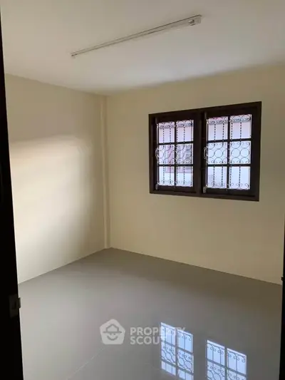 Spacious empty room with tiled floor and barred windows, ideal for customization.