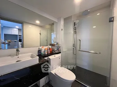 Modern bathroom with sleek fixtures and glass shower enclosure in a contemporary apartment.