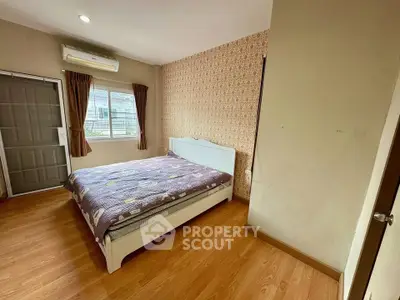 Spacious bedroom with wooden flooring and large window for natural light.