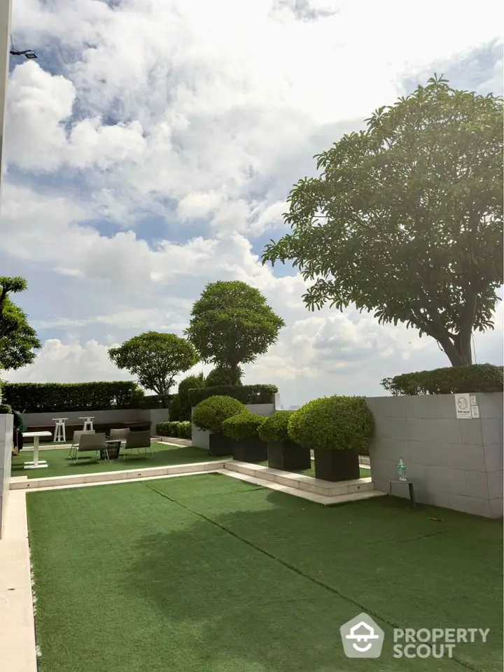 Stunning rooftop garden with lush greenery and seating area under a bright sky.