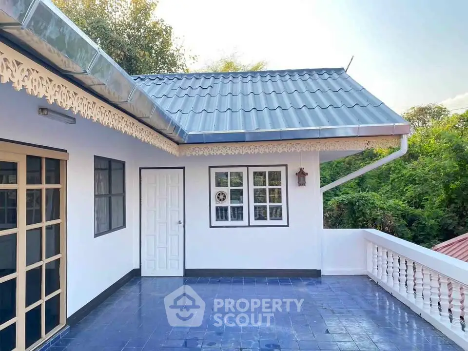 Charming house exterior with spacious balcony and decorative roof details.