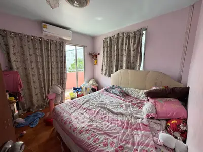 Cozy bedroom with pink decor and balcony access, featuring air conditioning and natural light.