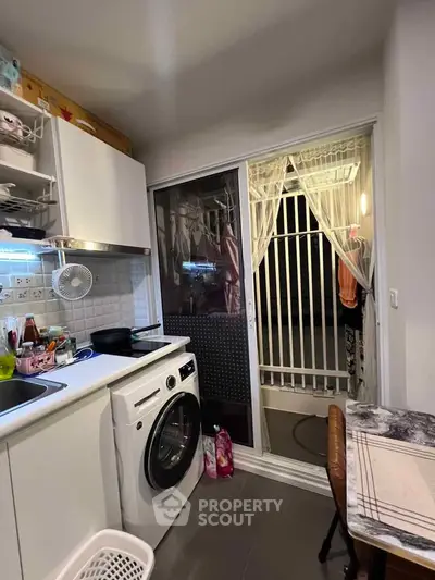 Compact kitchen with washing machine and balcony access in modern apartment
