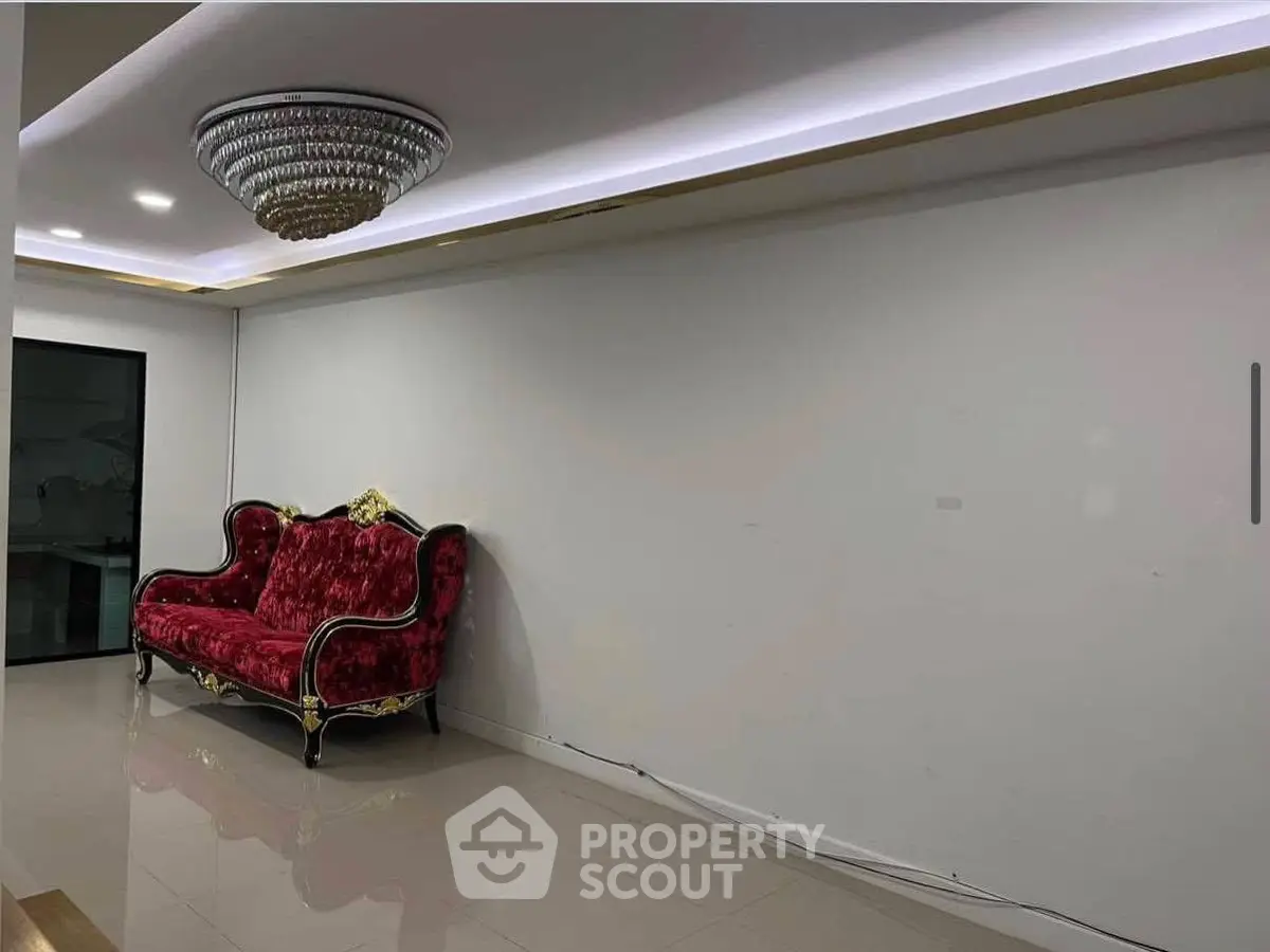 Elegant living room with luxurious red velvet sofa and modern chandelier.