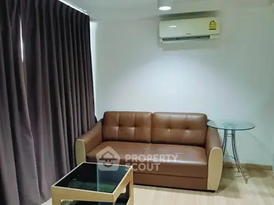 Cozy living room with brown leather sofa and modern glass table, featuring elegant curtains and air conditioning.