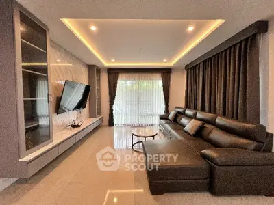 Luxurious modern living room with sleek leather sofa and large TV, perfect for relaxation.