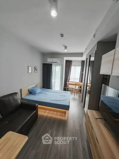 Modern studio apartment with sleek design and ample natural light, featuring a cozy bed and stylish furnishings.