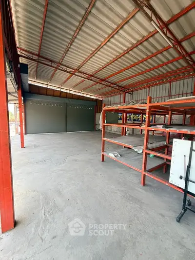 Spacious industrial warehouse with metal shelving and large garage doors, ideal for storage or business operations.