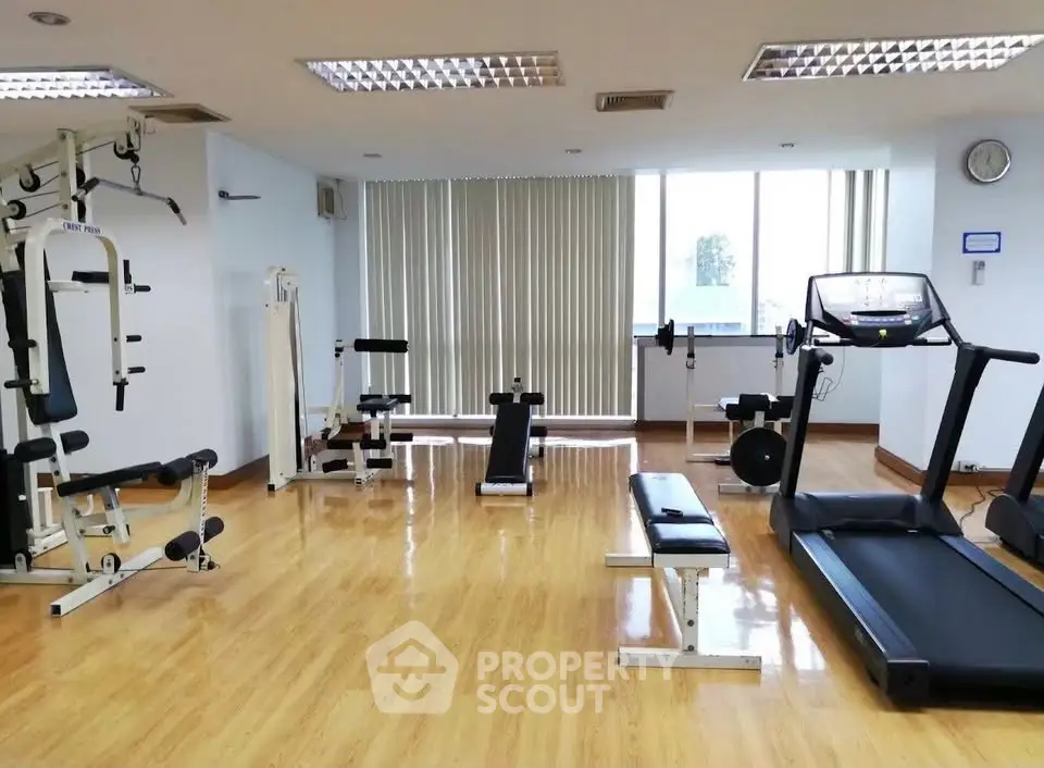 Spacious gym with modern equipment and bright natural lighting.
