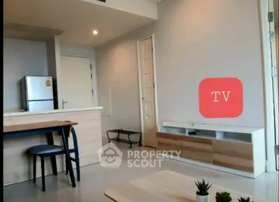Modern living room with sleek furniture and open kitchen layout, featuring a stylish TV stand and dining area.