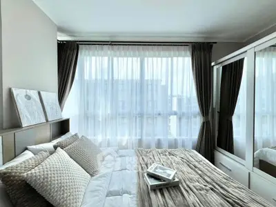 Elegant bedroom with large windows, modern decor, and cozy bedding in a bright apartment.