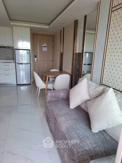 Modern living room with sleek kitchen and dining area, featuring elegant decor and ample natural light.