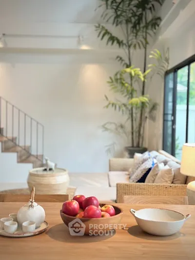 Elegant living room with modern decor and natural light, featuring a cozy seating area and stylish staircase.
