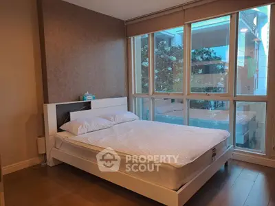 Spacious bedroom with large windows offering a serene view, featuring a modern bed and elegant decor.