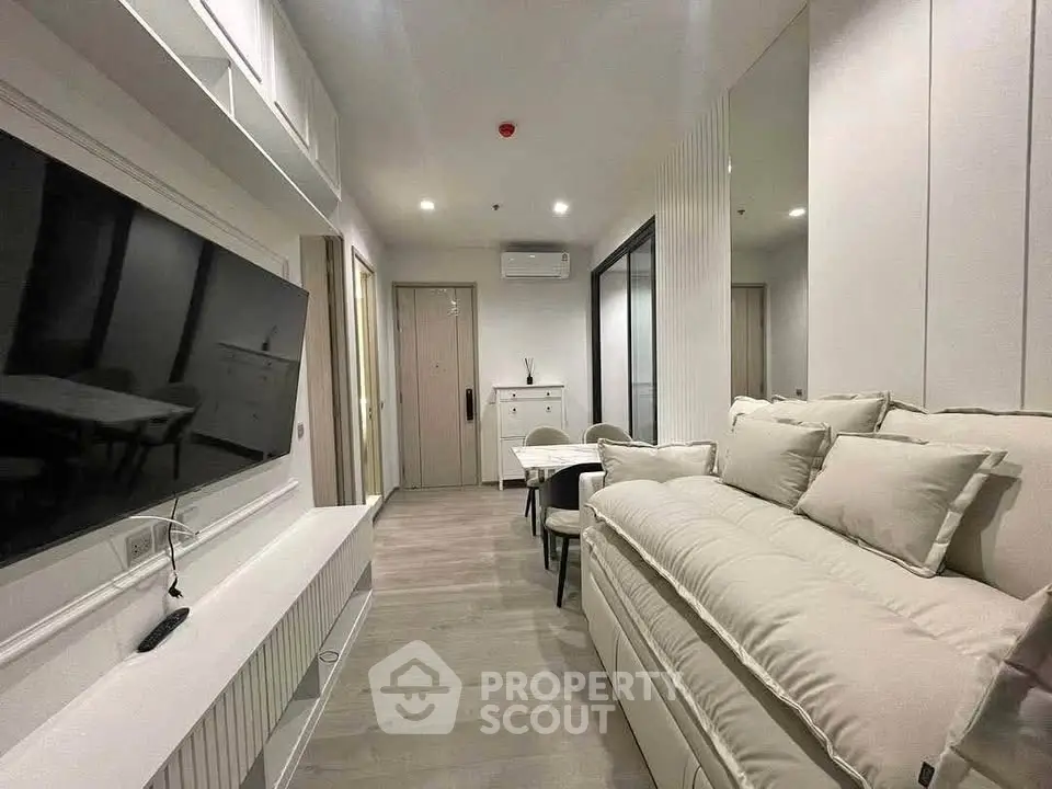 Modern living room with sleek design, featuring a large TV, cozy sofa, and elegant dining area.