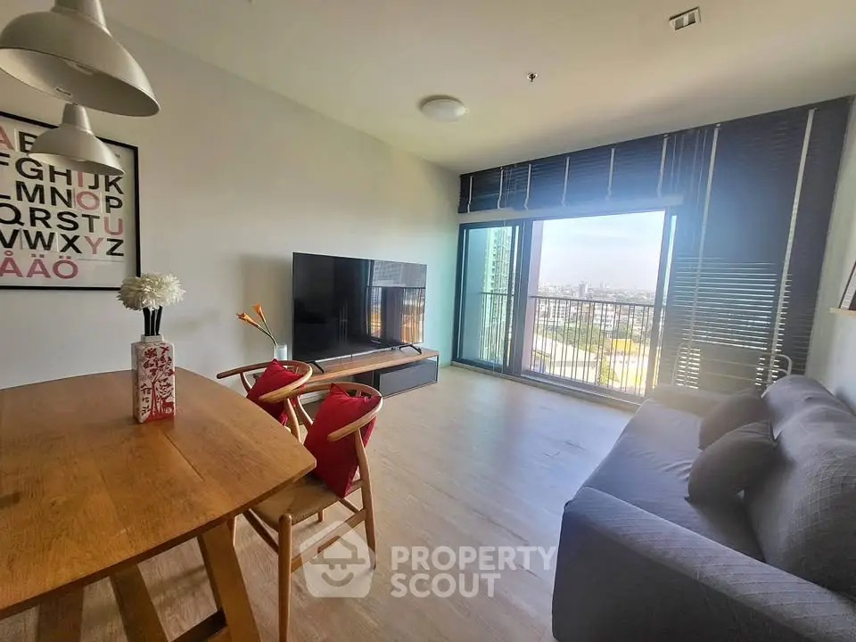 Modern living room with large TV, stylish furniture, and city view from balcony.