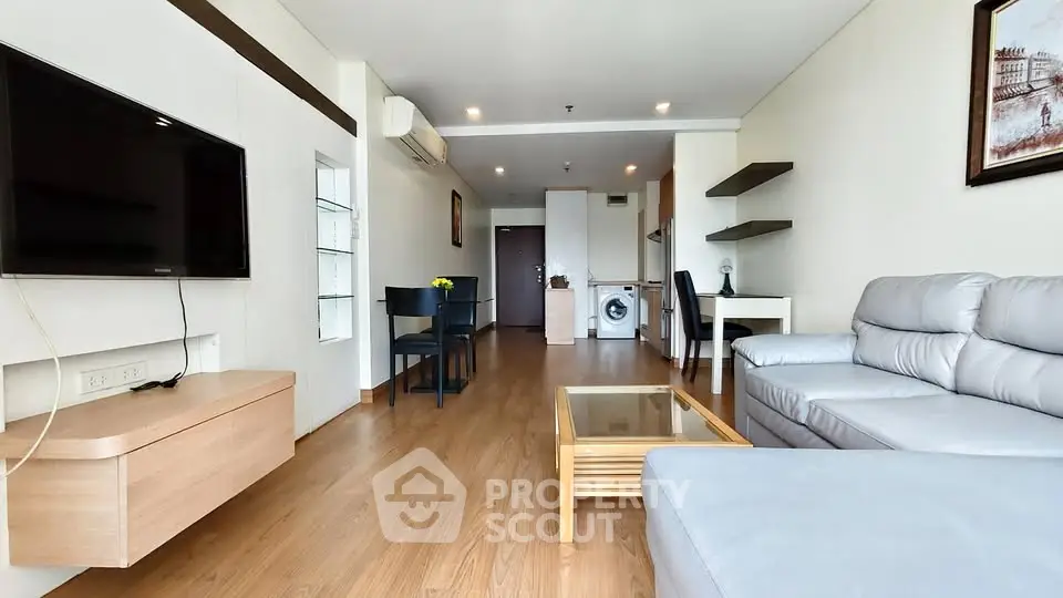Spacious modern living room with sleek furniture and built-in TV, featuring a washing machine in the background.