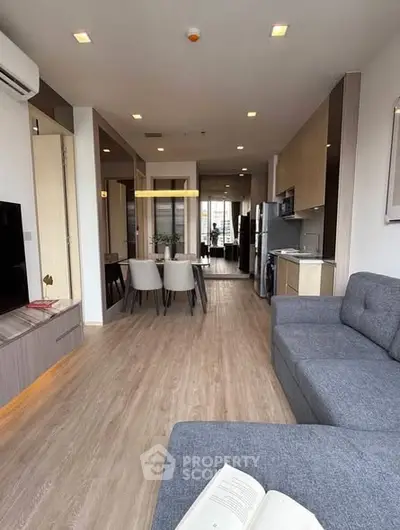 Modern open-plan living room with stylish dining area and sleek kitchen in a contemporary apartment.