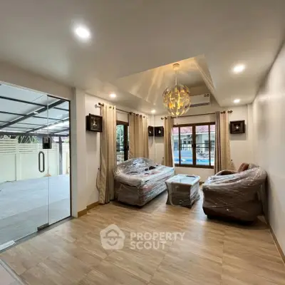 Spacious living room with modern lighting and large windows, offering a seamless indoor-outdoor flow.