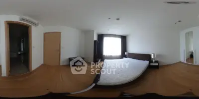 Spacious bedroom with wooden flooring and large window for natural light.