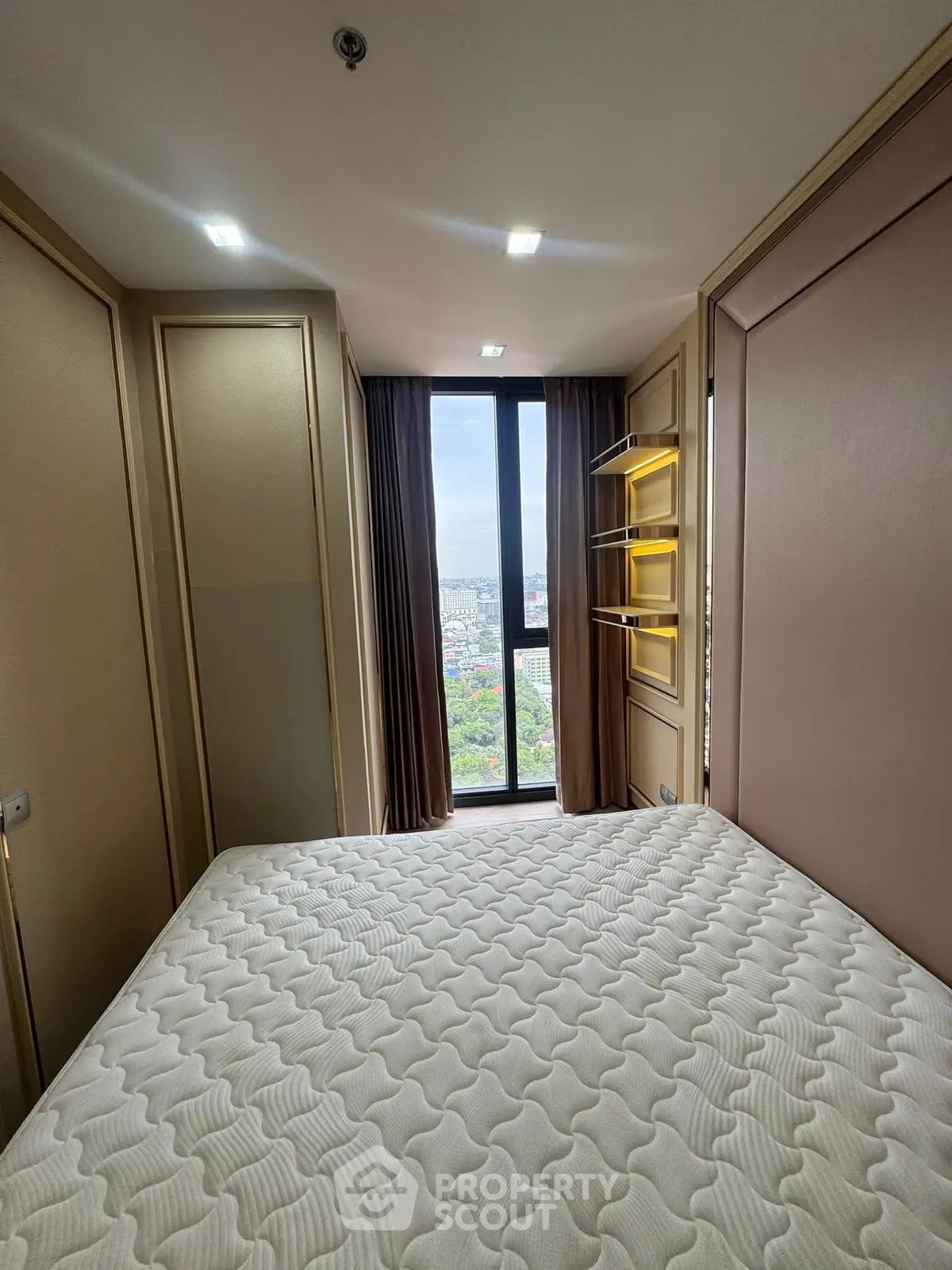 Cozy bedroom with large window offering stunning city view and modern lighting.