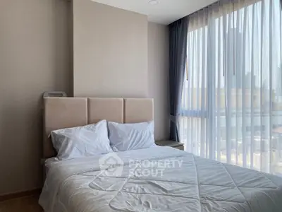 Bright and cozy bedroom with large window and modern decor.
