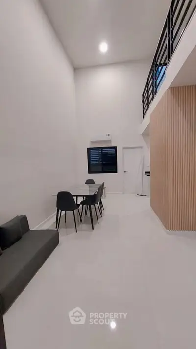 Modern minimalist living room with high ceiling and mezzanine, featuring sleek furniture and elegant design.