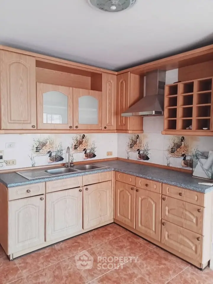Charming kitchen with wooden cabinets and decorative backsplash, featuring ample storage and modern range hood.