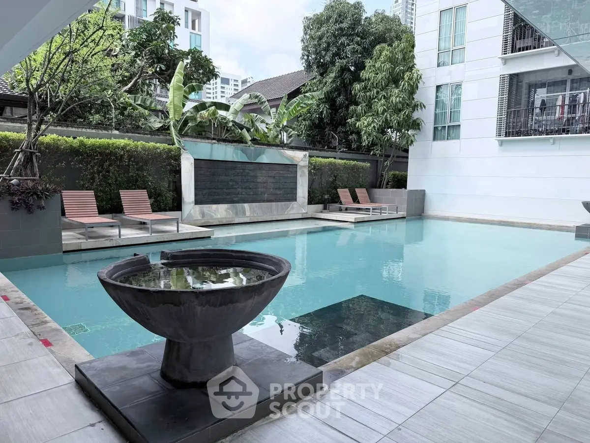 Luxurious modern pool area with stylish loungers and lush greenery in a high-end residential complex.