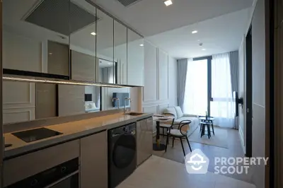 Modern open-layout kitchen and living area with sleek appliances and large windows.