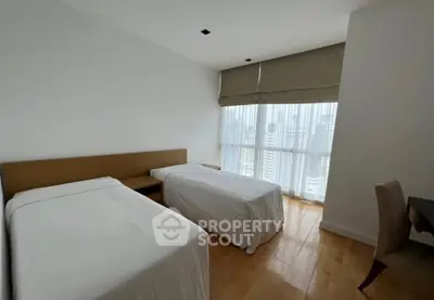 Modern bedroom with twin beds and city view, featuring sleek design and natural light.