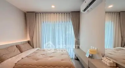 Modern bedroom with cozy bedding and natural light through large window.