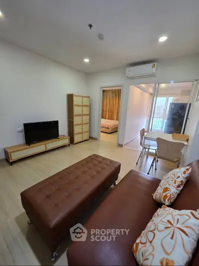 Modern living room with stylish furniture and open layout, featuring a cozy bedroom view.