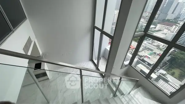 Modern high-rise apartment with stunning city view and sleek glass railing staircase.