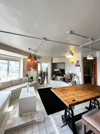 Spacious living room with modern decor and natural light, featuring a cozy seating area and stylish lighting.