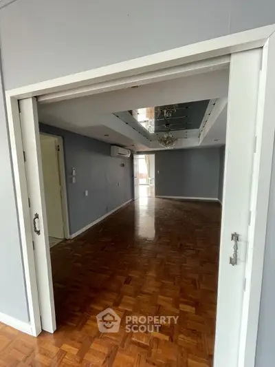 Spacious empty living room with wooden flooring and sliding doors, perfect for customization.