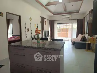 Spacious open-plan living room with modern kitchen island and large windows.